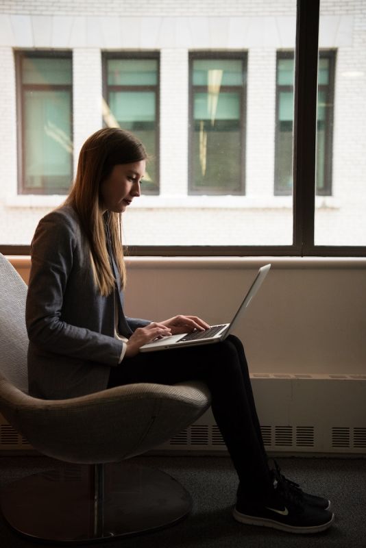 Woman Sits and Use Laptop Computer Near Window